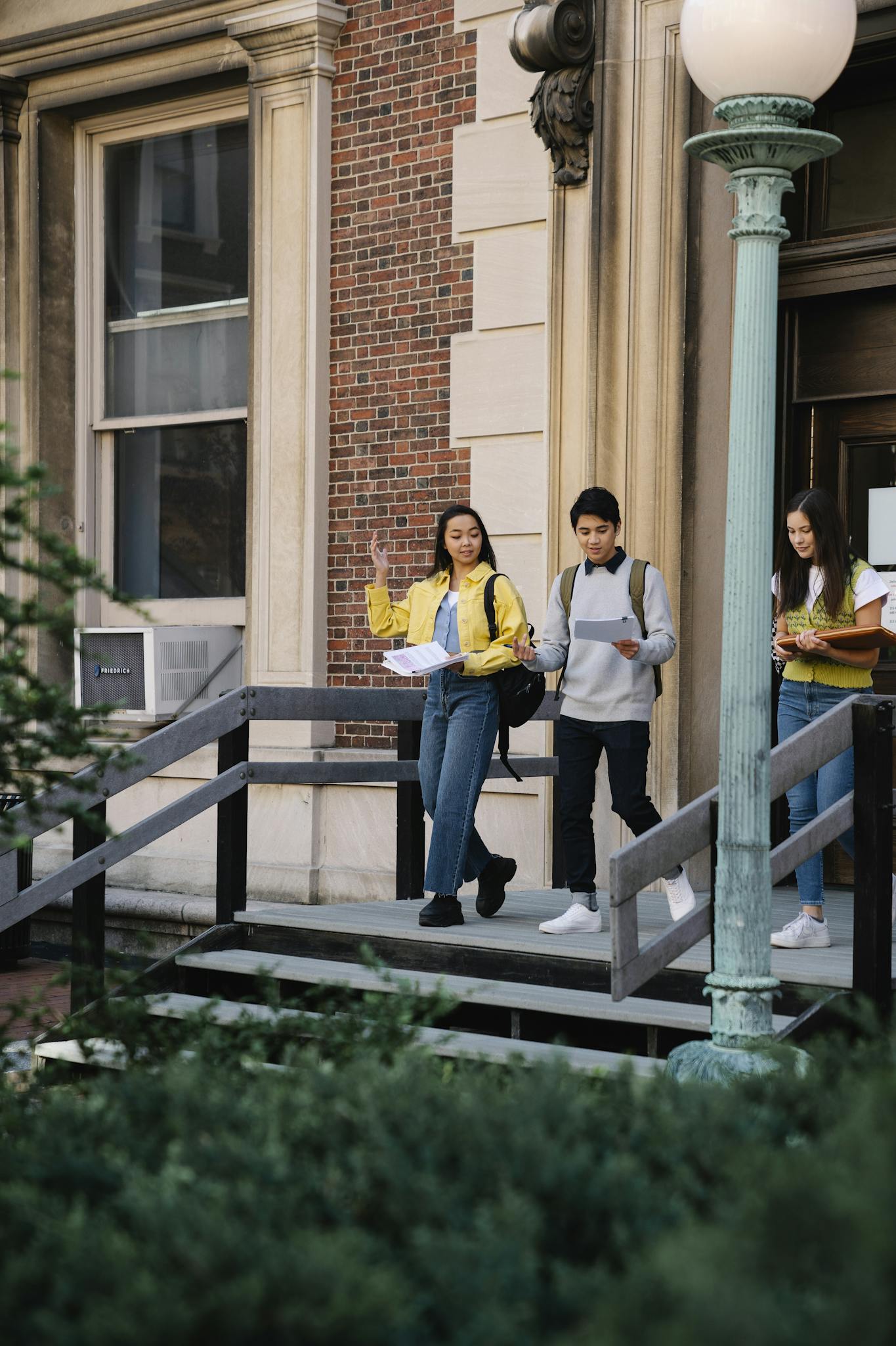 Group of diverse students leaving a university building, carrying books and talking.