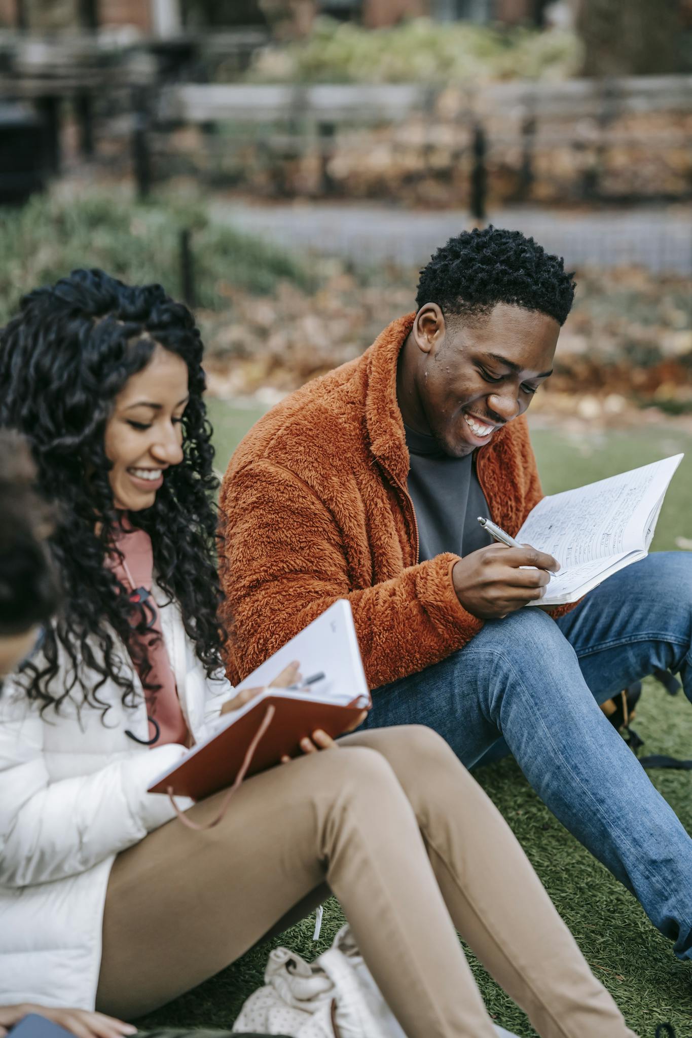 Students collaborate on assignments while seated on a campus lawn, enjoying a study session outdoors.
